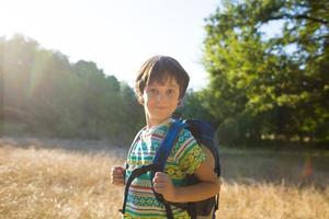 um menino com uma mochila caminha pela floresta foto