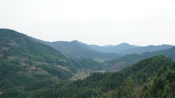 a bela vista das montanhas com a floresta verde e as nuvens se erguendo delas em um dia chuvoso no interior do sul da China foto