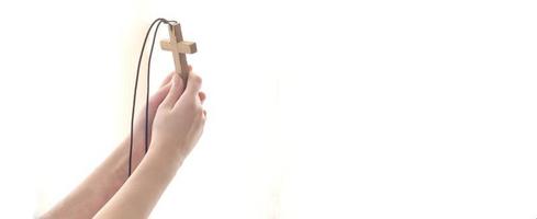 mãos estendidas com uma cruz para Deus na luz. foto
