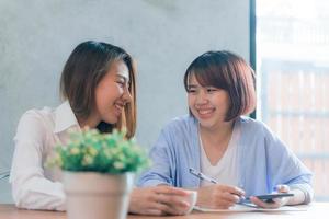 duas mulheres de negócios jovens sentadas à mesa no café. mulheres asiáticas usando laptop e café. freelancer trabalhando em uma cafeteria. trabalhando fora do estilo de vida do escritório. reunião individual. foto