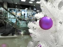 muito peri brinquedo roxo em uma árvore de Natal branco. árvore de natal na loja foto