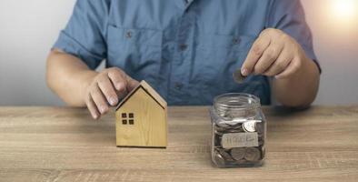 homem colocando dinheiro no banco do frasco, economize para futuras compras de casa. planejamento de economia de dinheiro, negócios, finanças, diretrizes de pagamento, conceito financeiro. foto