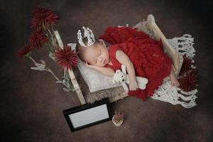 bebezinho coberto com roupas vermelhas com bandagem na cabeça deitado dormindo no travesseiro branco foto