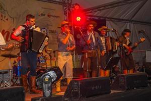 canela, brasil - 21 de julho de 2019. músicos com roupas típicas cantando canções tradicionais em palco de festival folclórico em canela. uma pequena cidade charmosa muito apreciada pelo seu ecoturismo. foto