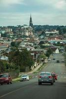 canela, brasil - 21 de julho de 2019. rua com carros indo em direção à paisagem urbana de casas e campanário da igreja em canela. uma pequena cidade charmosa muito apreciada pelo seu ecoturismo. foto