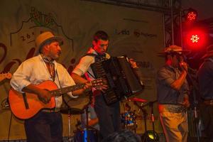 canela, brasil - 21 de julho de 2019. músicos com roupas típicas cantando canções tradicionais em palco de festival folclórico em canela. uma pequena cidade charmosa muito apreciada pelo seu ecoturismo. foto