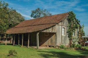 bento goncalves, brasil - 12 de julho de 2019. fachada de um antigo barraco charmoso de madeira em estilo rural tradicional com vegetação exuberante, próximo ao bento goncalves. foto