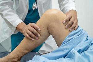 Médico fisioterapeuta examinando, massageando e tratando o joelho e a perna do paciente sênior no hospital de enfermagem da clínica médica ortopedista.
