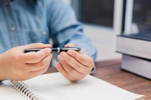 mulher segurando uma caneta sentada em uma mesa escrevendo foto