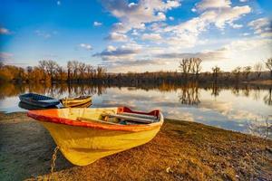 velho barco amarelo no chão perto do lago foto