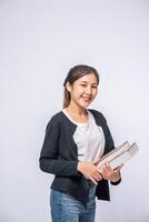 jovem sorrindo alegremente em uma camisa preta e calça jeans, segurando um livro e sorrindo alegremente. foto