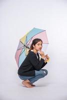 mulher em uma camisa preta sentada e abrindo um guarda-chuva foto