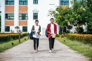 estudantes masculinos e femininos usam uma máscara facial e ficam em frente à universidade. foto