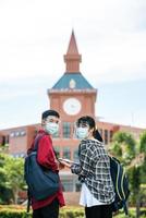 alunos do sexo masculino e feminino usam máscaras e ficam em frente à universidade. foto