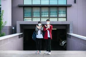 alunos do sexo masculino e feminino usam máscaras e ficam em frente à universidade. foto