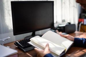 empresário lendo e escrevendo livro no trabalho foto