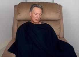 homem maduro tirando uma soneca no meio do dia em uma poltrona foto
