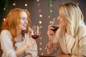 casal de lésbicas jantando em um restaurante. garotas bebem vinho e conversam foto