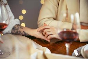 casal de lésbicas jantando em um restaurante. close-up das mãos de um casal apaixonado foto