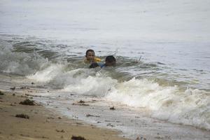 sorong, oeste de papua, indonésia, 12 de dezembro de 2021. meninos brincando contra as ondas na praia foto
