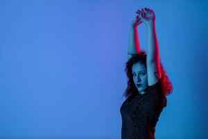 retrato emocional, uma menina com as mãos para cima. luz de cor, azul e vermelho. tiro do estúdio. copyspace para inserir texto