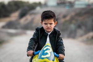 garotinho zangado andando em um brinquedo de motocicleta foto