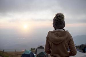 verso jovem em pé assistir ao nascer do sol em phu thap boek phetchabun, tailândia. foto