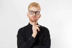 homem pensando, cabelo ruivo homem em óculos elegantes, pensamento sério, retrato pensativo em estúdio isolado sobre fundo branco, jovem atraente de camisa preta foto