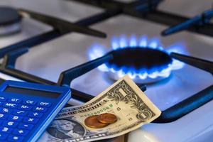 escassez e crise do gás. dinheiro e uma calculadora no fundo de um fogão a gás foto