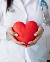 mulher médica ou cientista segurando um grande coração vermelho nas mãos foto
