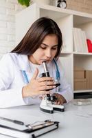 jovem médica ou cientista usando microscópio foto