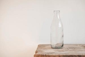 frasco de vidro transparente na mesa de madeira no fundo da parede branca. cópia, espaço vazio para texto foto