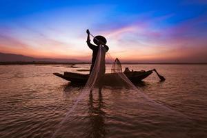 pescador asiático com seu barco de madeira no rio da natureza no início da manhã antes do nascer do sol
