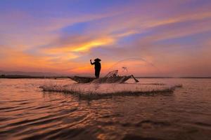pescador asiático com seu barco de madeira no rio da natureza no início da manhã antes do nascer do sol