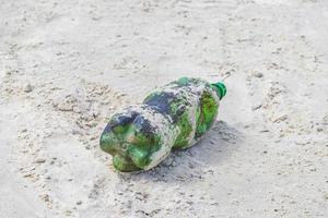 garrafa de plástico encalhada lavada com poluição de lixo na praia brasil. foto