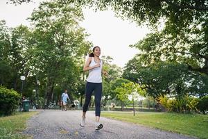 mulher bonita jovem corredor asiático saudável em roupas esportivas, correndo e correndo na calçada perto do lago, no parque, pela manhã. fitness de estilo de vida e mulheres ativas exercem no conceito de cidade urbana. foto