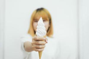 retrato interior de uma jovem mulher asiática bonita comendo sorvete no verão. mulher com as mãos segurando casquinha de waffle de sorvete derretendo. conceito de mulher da ásia estilo de vida foto