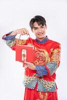 homem usa cheongsam pronto para dar uma bolsa vermelha para a irmã por surpreender nos dias tradicionais foto
