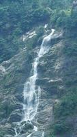 a bela vista do campo com a cachoeira fluindo nas montanhas após o dia chuvoso foto