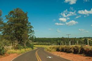 pardinho, brasil - 31 de maio de 2018. estrada asfaltada no campo em paisagem montanhosa coberta por prados e árvores, em um dia ensolarado perto do pardinho. uma pequena aldeia rural no interior do estado de são paulo. foto