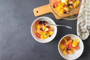 salada de frutas em tigelas brancas em uma mesa preta foto