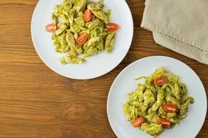 macarrão com pedaços de frango, pesto de manjericão e tomate. jantar delicioso. foto