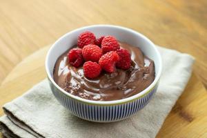 pudim de chocolate com framboesas em uma mesa de madeira. foto