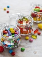 doces coloridos em potes na mesa foto