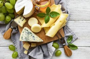 vários tipos de queijo em um fundo branco de madeira foto