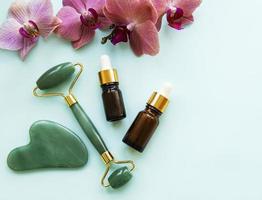 Rolo de jade para massagem facial com produto cosmético foto