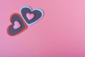 dois corações em um fundo rosa no canto superior esquerdo e dois corações pequenos. o conceito de dia dos namorados. foto