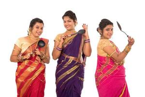 jovens indianas tradicionais segurando utensílios de cozinha em fundo branco foto