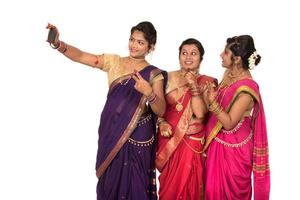 garotas indianas tradicionais tirando selfie com smartphone em fundo branco foto