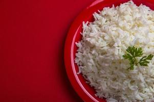 arroz basmati branco puro cozido em um prato vermelho sobre fundo vermelho foto